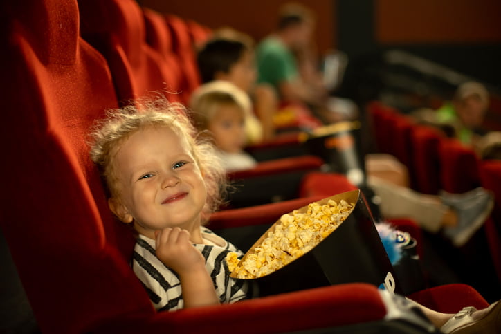 Jente kosar seg med popkorn på kino.