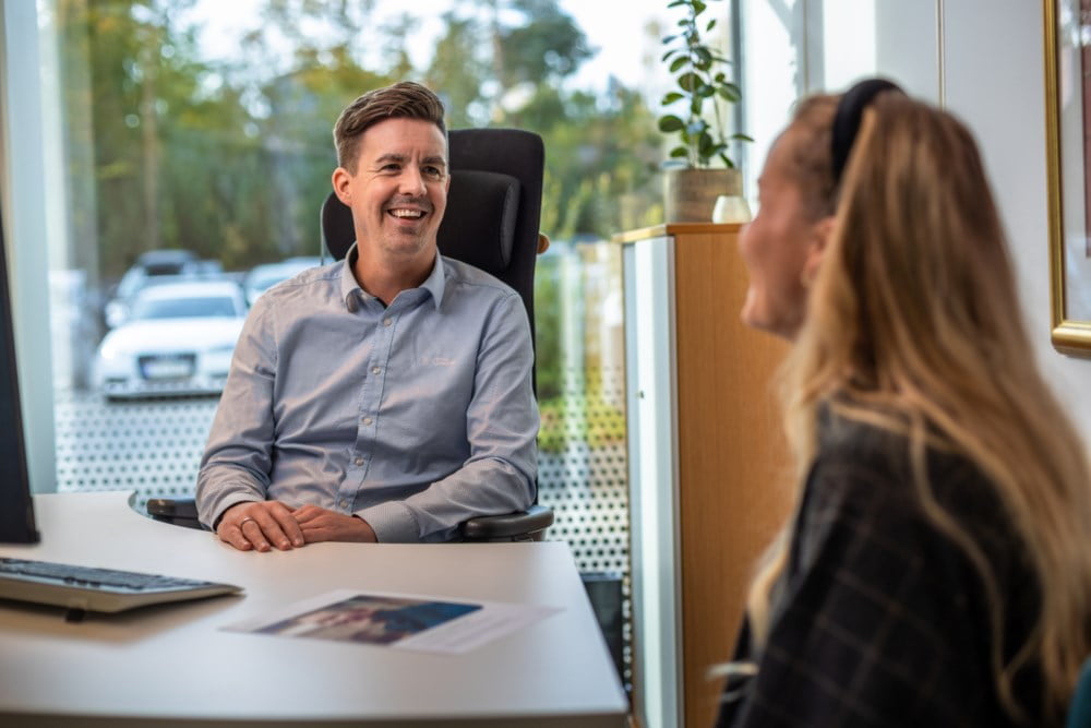 Rådgiverprat i banklokale med smilende rådgiver og kvinne