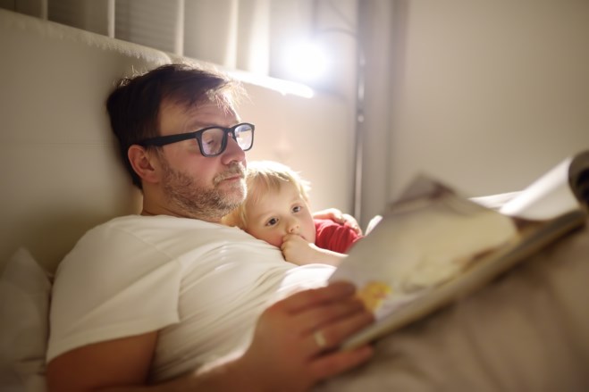 Far leser godnattfortelling for sønnen sin i sengen